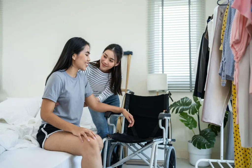 Carer helping disabled woman out of bed and into wheelchair